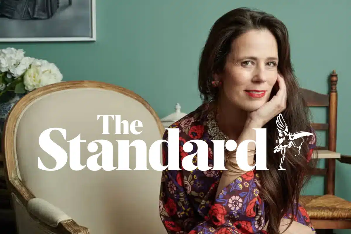 Gillian McCallum seated against a green wall with The Standard logo, from her piece on alternative family structures